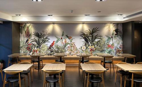 a restaurant with tables and chairs in front of a mural at Just Sleep Hualien ZhongZheng in Hualien City