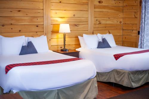 two beds in a room with wooden walls at Crooked River Ranch Cabins in Terrebonne