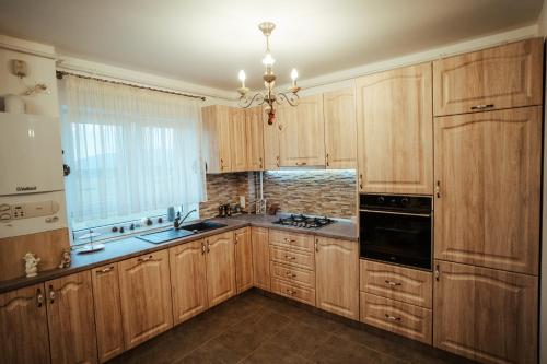 una cucina con armadi in legno e lampadario pendente di Luxury Apartments a Şelimbăr