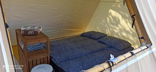 a small bed in a tent with a table at Na vrtu K25 in Gradac