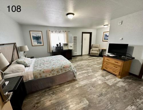 Schlafzimmer mit einem Bett, einem Schreibtisch und einem TV in der Unterkunft Alaska Angler's Inn in Soldotna