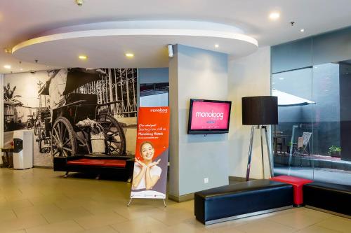 eine Lobby mit einem TV und einer Couch in einem Gebäude in der Unterkunft Monoloog Hotel Palembang in Palembang