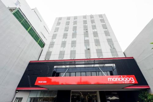 a building with a red sign in front of it at Monoloog Hotel Palembang in Palembang