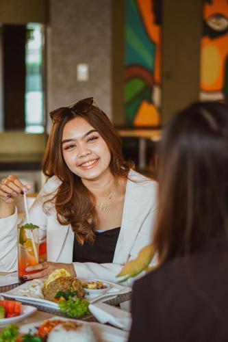 a woman sitting at a table with a plate of food at Ascent Hotel & Cafe Malang in Malang