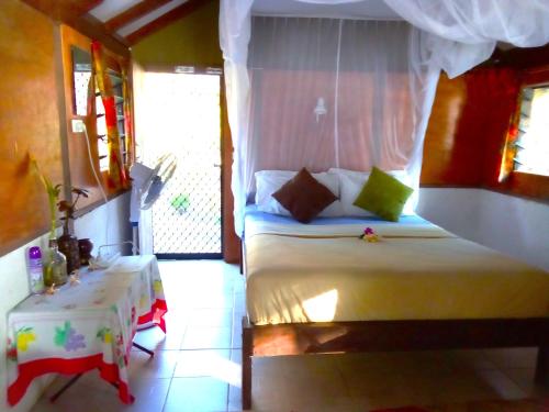 a bedroom with a white bed and a table at Vatupau Beachfront Bungalows in Port Vila