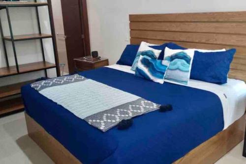 1 cama con sábanas azules y almohadas azules en Nuevo y Cómodo Departamento en el corazón de la Zona Dorada, en Mazatlán