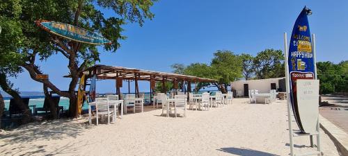 eine Reihe von Stühlen am Strand neben dem Wasser in der Unterkunft The Trawangan Resort in Gili Trawangan