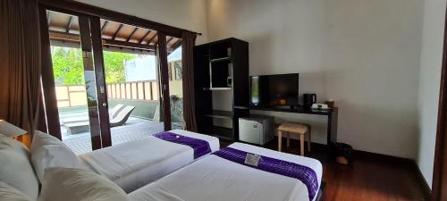 a living room with two beds and a television at The Trawangan Resort in Gili Trawangan