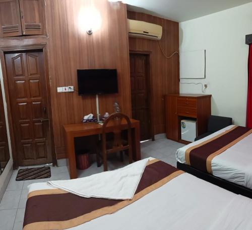 a hotel room with two beds and a desk and a television at Hotel Skylink in Dhaka