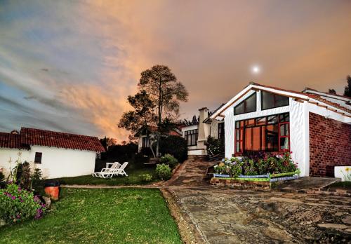 a house with a garden and a cloudy sky at Hotel Cabañas San Cayetano in Paipa
