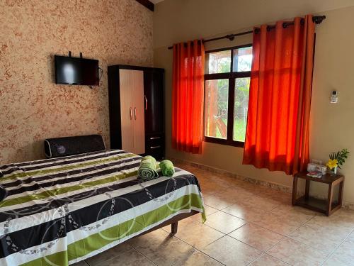 a bedroom with a bed and a window with red curtains at Quinta Los Pinos Cotoca in Cotoca