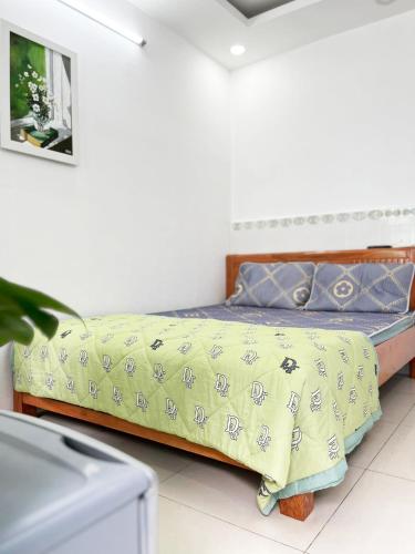 um quarto com uma cama com um cobertor amarelo em Homestay Ms. Hoa em Ho Chi Minh