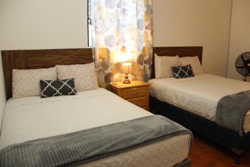 a bedroom with two beds and a lamp on a night stand at Real Hostal in Guatemala