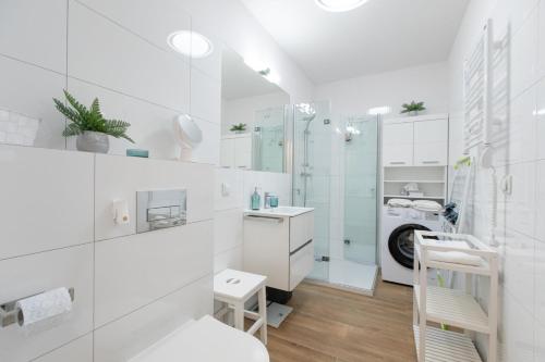 a white bathroom with a sink and a shower at Apartament Modern by Major Domus Club in Dziwnów