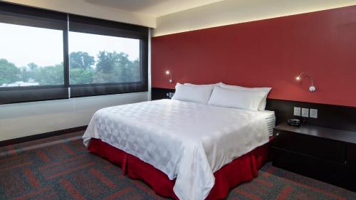 a bedroom with a large bed with a red wall at Holiday Inn Mexico Dali Airport by IHG in Mexico City