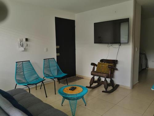 - un salon avec un canapé, des chaises et une télévision dans l'établissement hermoso apartamento amoblado, à La Tebaida