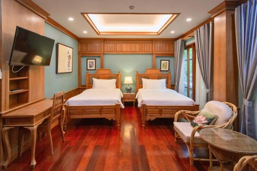 チェンマイにあるRich Garden House Hotelのベッド2台、テーブル、テレビが備わる客室です。