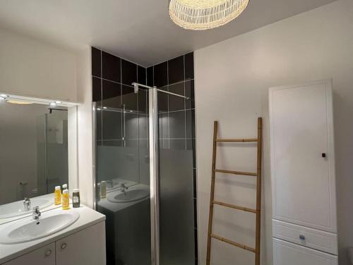 uma casa de banho com um chuveiro, um lavatório e um espelho. em Appartement Le Boïate YourHostHelper em La Teste-de-Buch