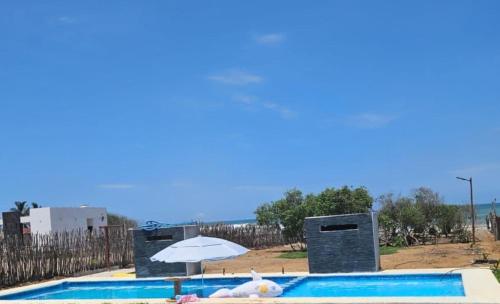 ein Pool mit einem Regenschirm und einem weißen ausgestopften Tier in der Unterkunft Tres Velas Surf in Celestino Gasca