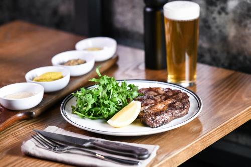 a table with a plate of food and a glass of beer at Powerhouse Hotel Tamworth by Rydges in Tamworth