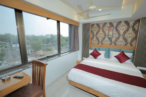 a bedroom with a bed and a desk and windows at HOTEL RK FORTUNE in Ahmedabad
