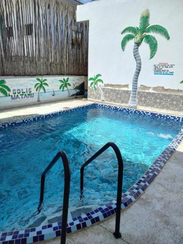 una piscina con una palmera en la pared en Rhino Apartment Watamu, en Watamu