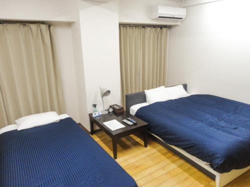 a bedroom with a bed and a table with a blue blanket at HOTEL LiVEMAX BUDGET Nagoya in Nagoya