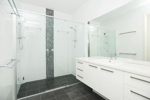 uma casa de banho branca com um chuveiro e um lavatório. em Executive Accommodation Absolute Beach Front em Middleton