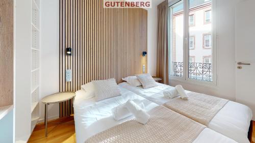 a white bedroom with two beds and a window at Résidence 12 Rue de la Mesange - City Center in Strasbourg