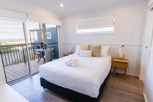 a bedroom with a large white bed and a balcony at BIG4 Tasman Holiday Parks - Racecourse Beach in Bawley Point