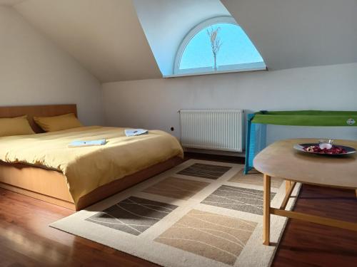 Schlafzimmer mit einem Bett, einem Tisch und einem Fenster in der Unterkunft Lend apartman in the garden in Miercurea Ciuc