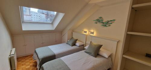 two beds in a small room with a window at La Buhardilla de la Escalerona - 2 Hab - VUT-4354-AS in Gijón