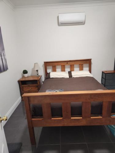 1 dormitorio con cama de madera y mesita de noche en City Villa 41 Blende st Broken Hill NSW 2880, en Broken Hill