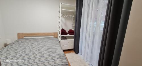 a small bedroom with a bed and a window at Apartamentai Kalno namai Juodkrantėje in Juodkrantė