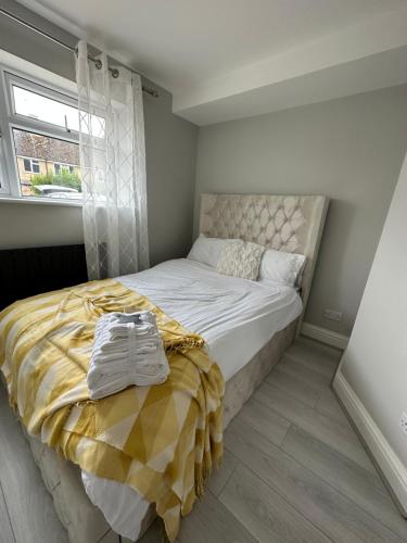 a bedroom with a bed with a yellow blanket and a window at Beautiful 2bedroom apartment in Cassington
