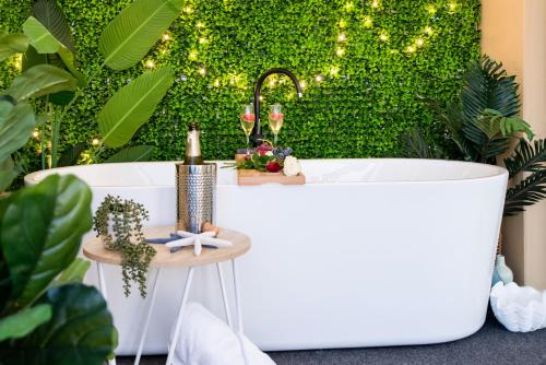 uma banheira em frente a uma parede verde com luzes em Bella Paradiso em Airlie Beach