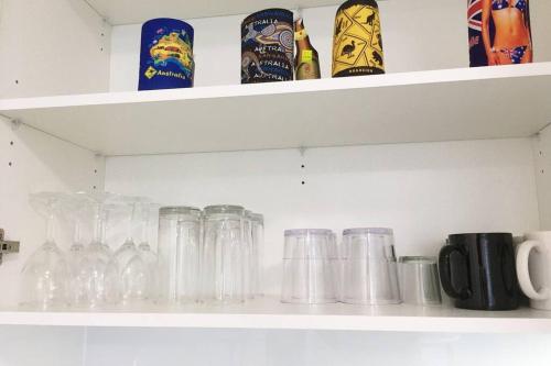 a shelf full of glass jars and cups at Bribie Getaway in Bongaree