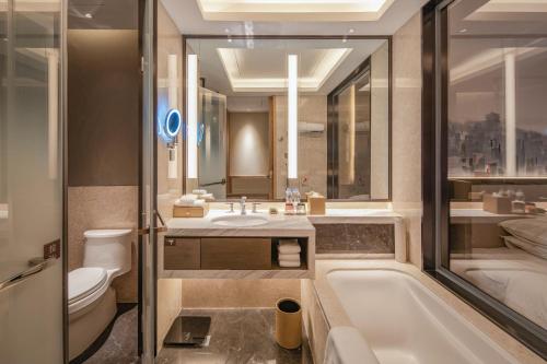 a bathroom with a tub and a toilet and a sink at Four Points by Sheraton Wuhan, Jiangxia in Wuhan