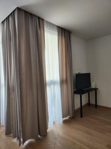 a room with a window with curtains and a computer on a desk at Prie Vilneles Apartment in Vilnius