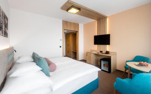 a hotel room with a white bed and a tv at Hunguest Hotel Gyula in Gyula
