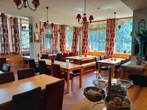 a restaurant with wooden tables and chairs and windows at Hotel Restaurant La Source in La Foux