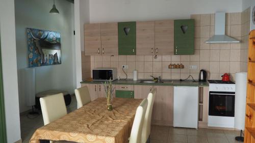 una cucina con tavolo e sedie e una cucina con armadi verdi di Tomaj Vendégház a Tomajmonostora