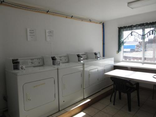 a laundry room with four washing machines and a table at All Seasons Campground in Ninilchik