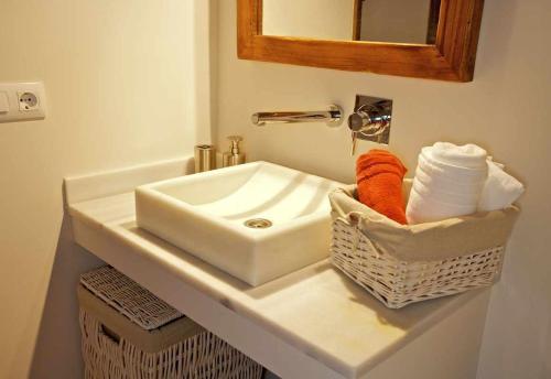 a bathroom sink with a basket of towels and a mirror at Mas Garriga Turisme Rural in Girona