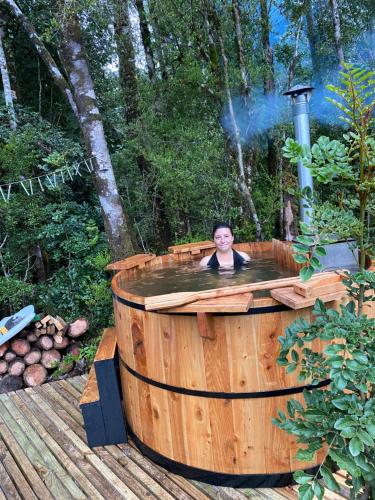 uma pessoa está em uma banheira de hidromassagem em uma madeira em Habitación en Casa Cumbres del Lago em Puerto Varas
