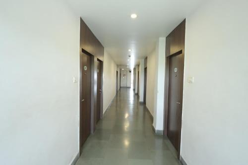 a corridor of a building with wooden doors and a long hallway at Hotel Hospice in Surat