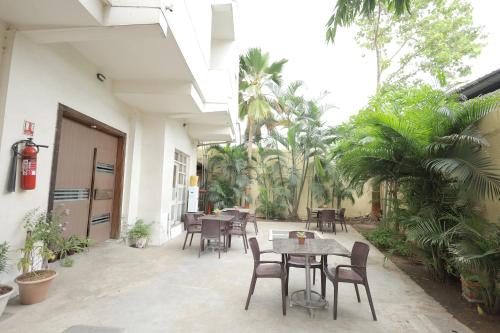 a patio with tables and chairs and palm trees at Hotel Hospice in Surat