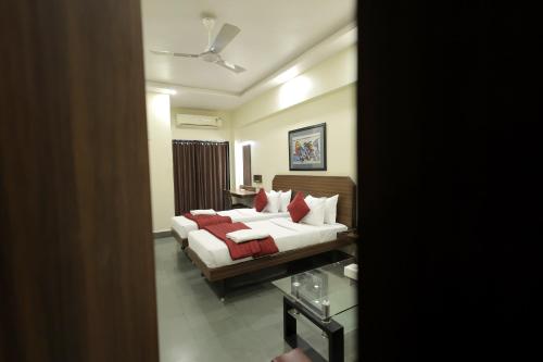 a bedroom with a bed with red pillows at Hotel Hospice in Surat