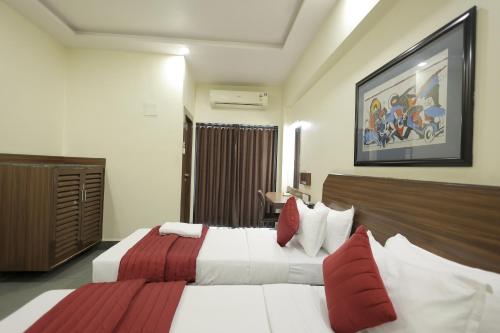 a hotel room with a bed with white and red pillows at Hotel Hospice in Surat