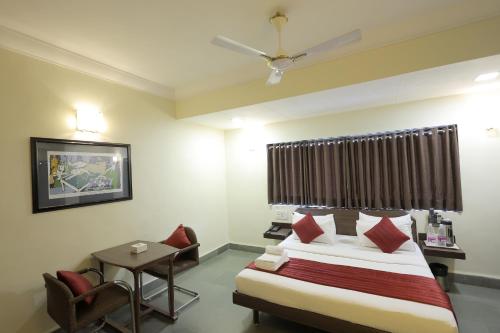 a bedroom with a bed and a table and chairs at Hotel Hospice in Surat